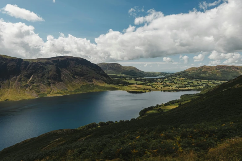 a large body of water sitting on top of a lush green hillside, by John Atherton, pexels contest winner, pre-raphaelitism, mountains and lakes, slate, thumbnail, high view