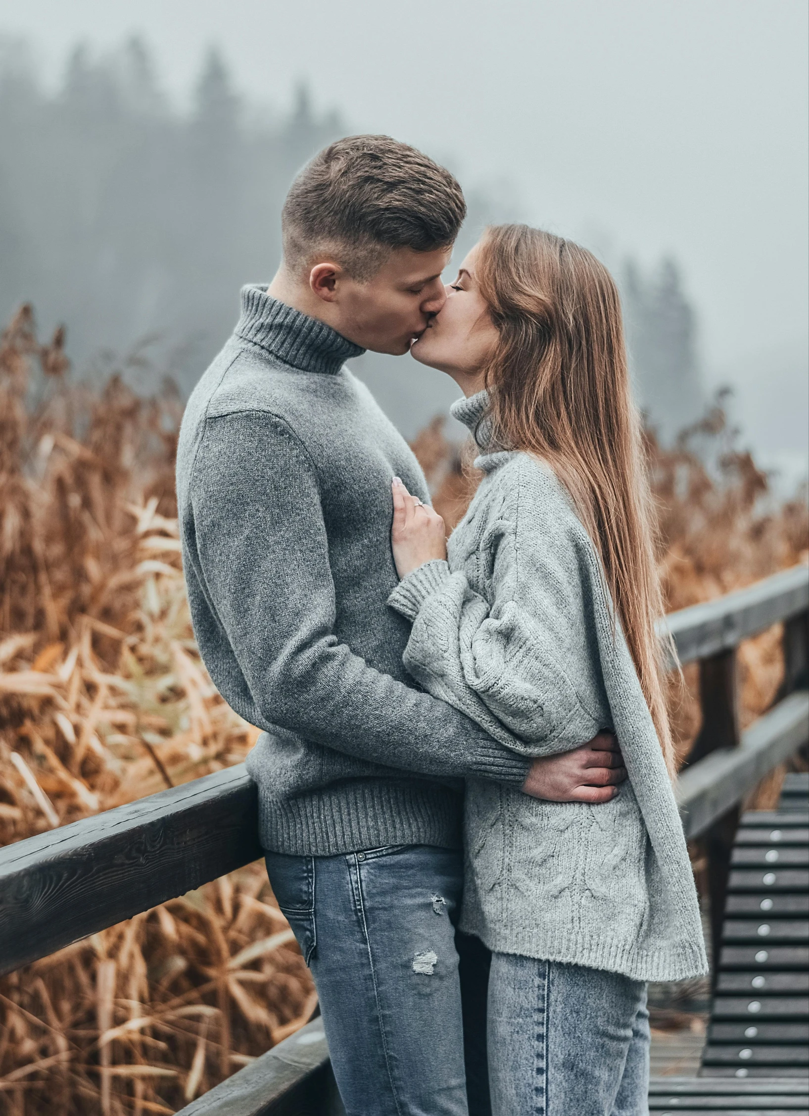 a man and woman standing next to each other on a bridge, pexels contest winner, romanticism, wearing a sweater, kisses are wordless spells, very attractive, 🚿🗝📝