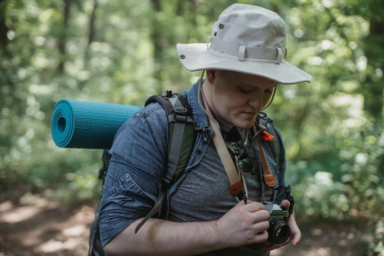 a man wearing a hat and holding a camera, by Meredith Dillman, trekking in a forest, avatar image