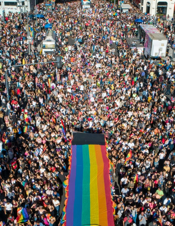 a large crowd of people walking down a street, sitting on top of a rainbow, 🚿🗝📝