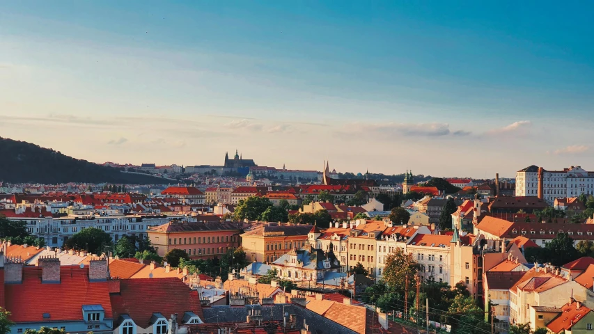 a view of a city from the top of a hill, by Emma Andijewska, pexels contest winner, art nouveau, orange and blue sky, square, summer evening, brown