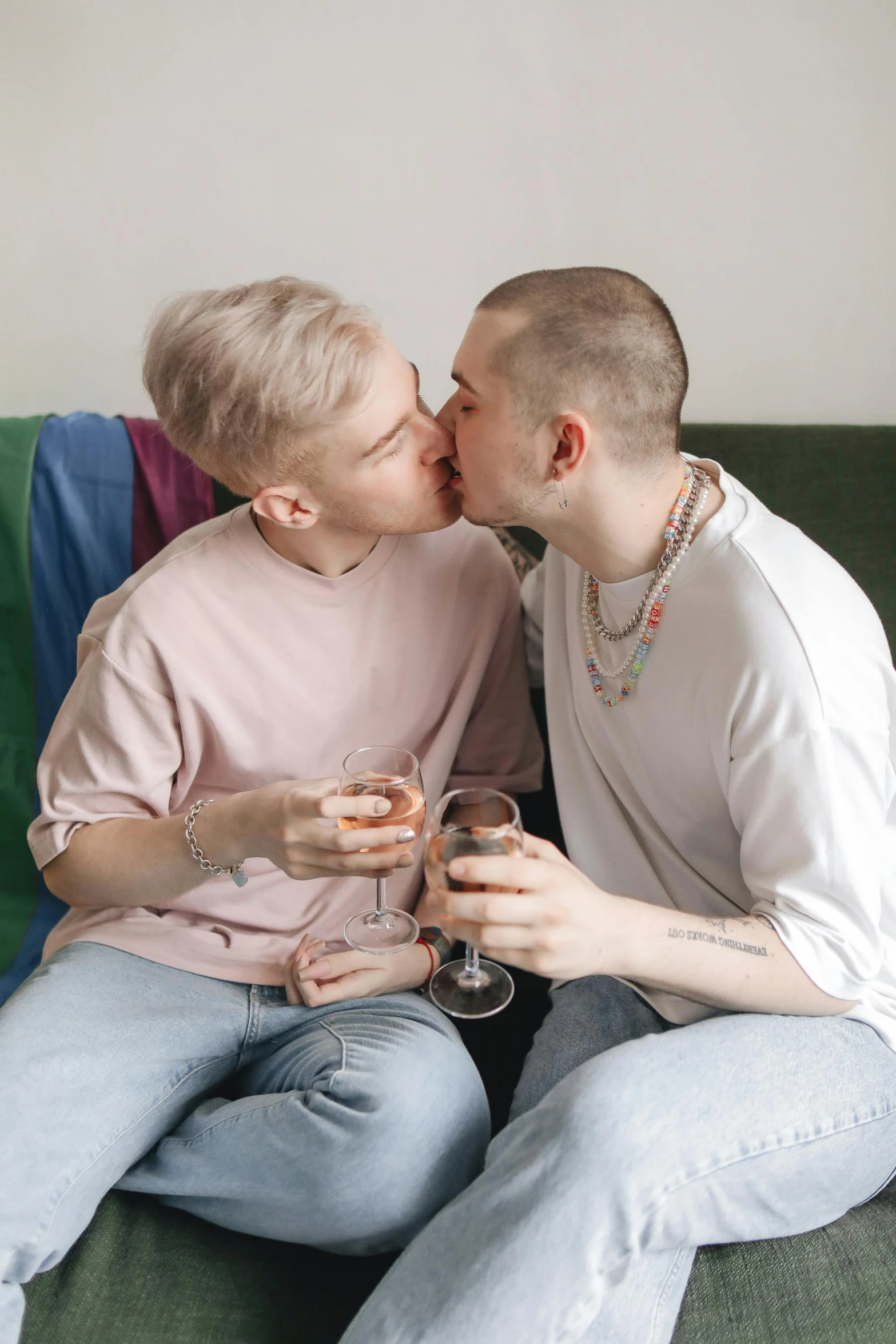 a couple of men sitting on top of a green couch, a photo, trending on pexels, renaissance, lesbian kiss, holding a drink, genderless, on a pale background