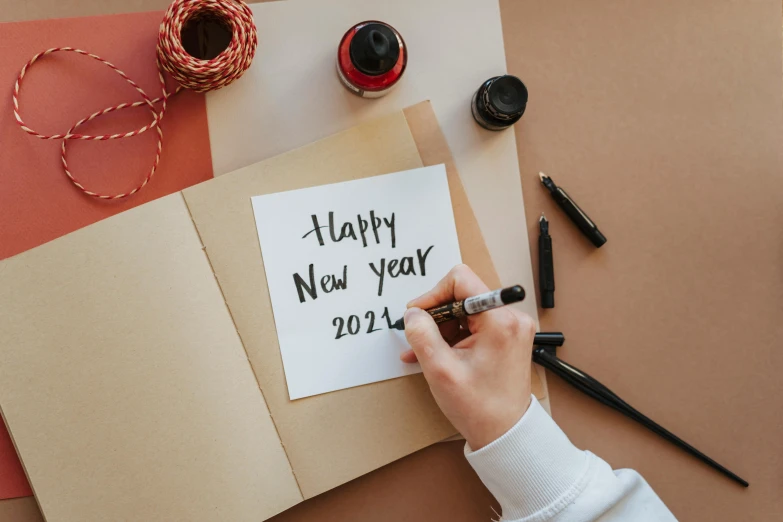 a person writing happy new year 2021 on a piece of paper, by Julia Pishtar, trending on pexels, brown, advertising photo, diecut, background image