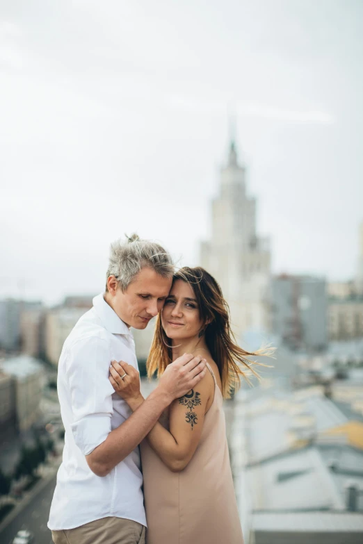 a man and woman standing next to each other on top of a building, a colorized photo, by Adam Marczyński, pexels contest winner, cuddling, ukrainian, headshot, square