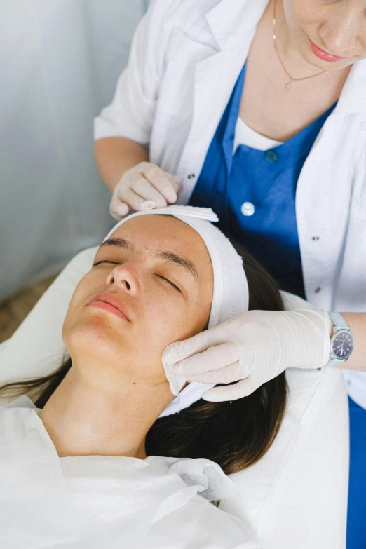 a woman getting a facial massage at a beauty salon, a picture, by Adam Marczyński, shutterstock, renaissance, made of lab tissue, scar on the cheek, white, thumbnail