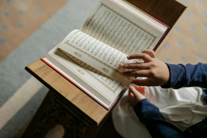 a person reading a book on a table, hurufiyya, religious imagery, thumbnail, fan favorite, schools