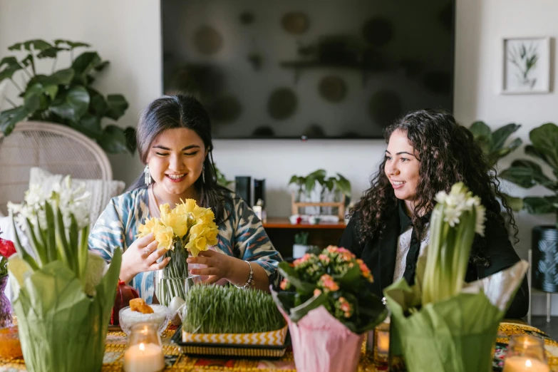 two women sitting at a table with vases of flowers, pexels contest winner, hurufiyya, at a birthday party, avatar image, carrying flowers, yellow and greens