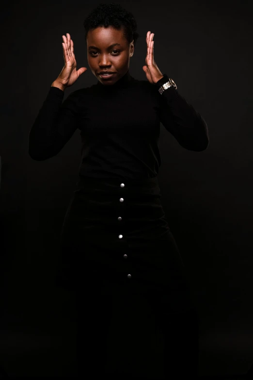 a woman standing in front of a black background, an album cover, inspired by Theo Constanté, pexels contest winner, man standing in defensive pose, black turtle neck shirt, black skin!!!, dave chappelle