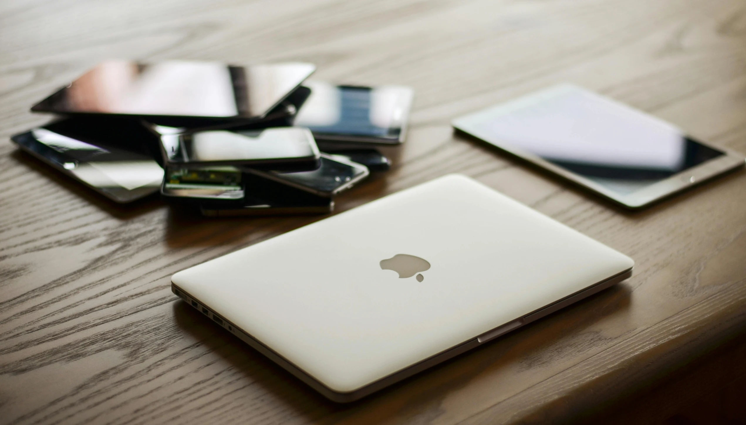 a laptop computer sitting on top of a wooden table, by Carey Morris, trending on pexels, many screens, smartphone, white, apple design