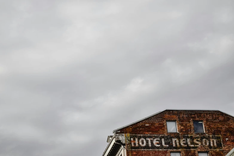 a sign that is on the side of a building, by Neil Boyle, pexels contest winner, hotel room, overcast skies, brick building, to hell with you