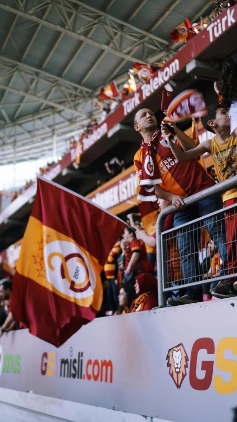 a crowd of people watching a soccer game, pexels, dark oranges reds and yellows, istanbul, waving robe movement, a handsome