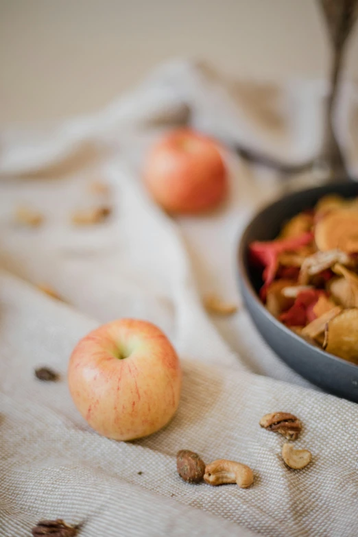 a pan filled with apples sitting on top of a table, inspired by Li Di, unsplash, dried leaves, crisps, linen, nut