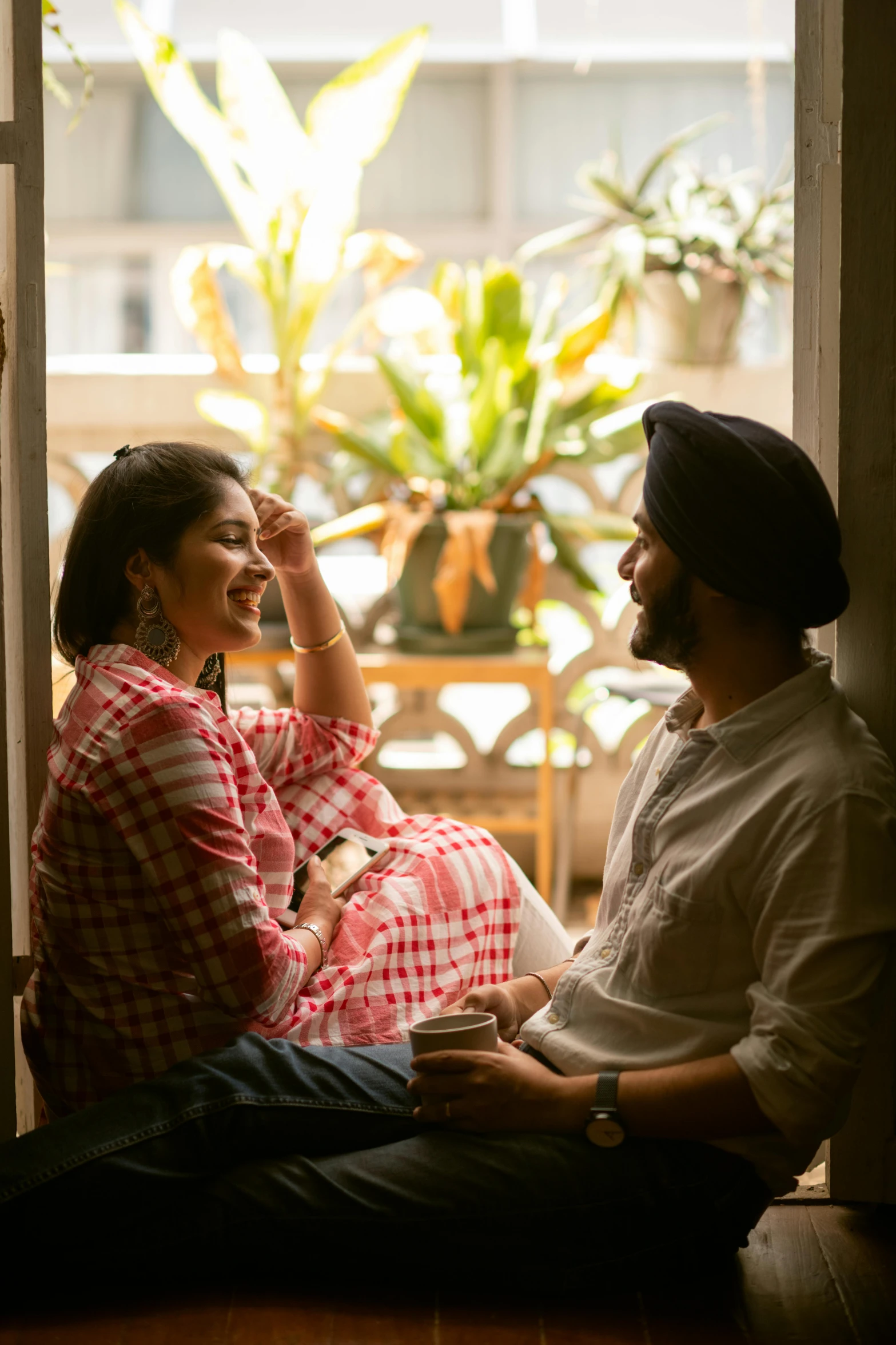 a man and a woman sitting on a window sill, by Manjit Bawa, pexels contest winner, smiling at each other, promotional image, indian, sitting in a lounge