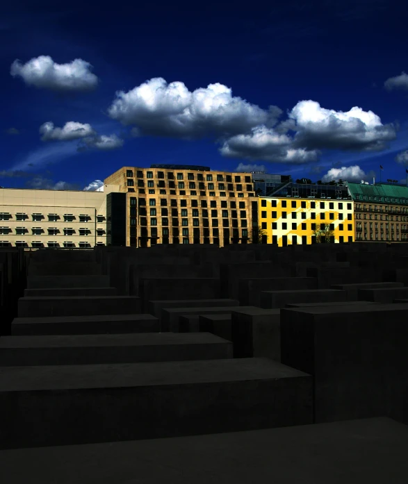 a row of concrete blocks with a building in the background, a matte painting, inspired by Anna Füssli, pexels contest winner, berlin secession, dramatic lighting and colors, taken in the late 2000s, untethered stelae, squares