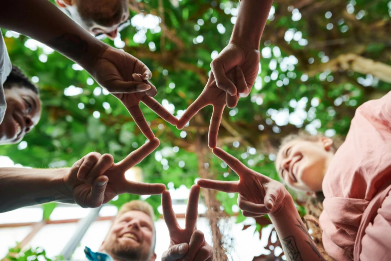 a group of people making a star with their hands, by Caroline Mytinger, pexels contest winner, entwined hearts and spades, peace sign, ecovillage, profile photo
