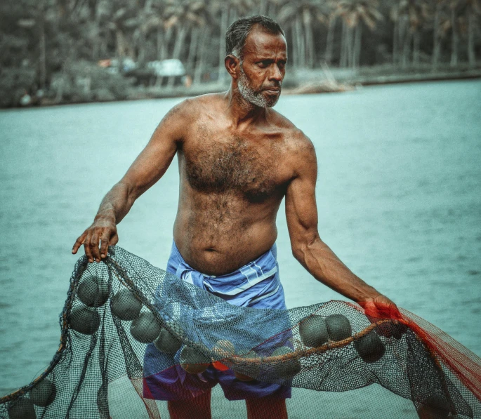 a man standing next to a body of water holding a net, coconuts, portrait image, trending photo, loincloth