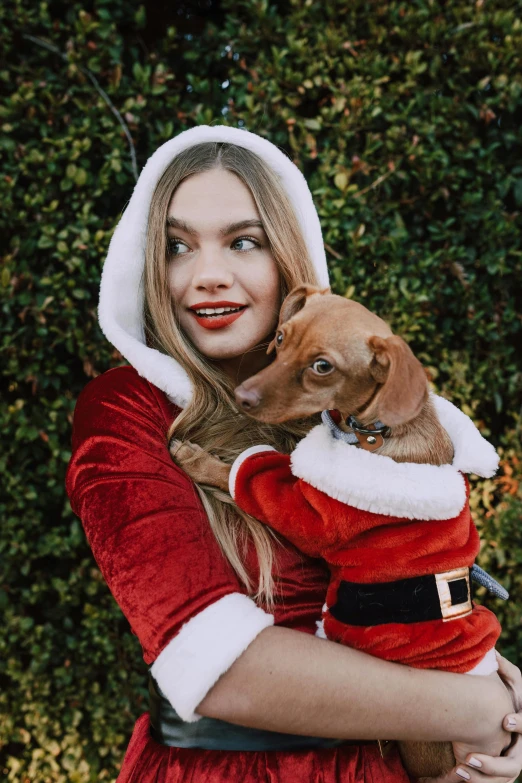 a woman in a santa outfit holding a dog, by Julia Pishtar, mrbeast, profile photo, barbara palvin, vine