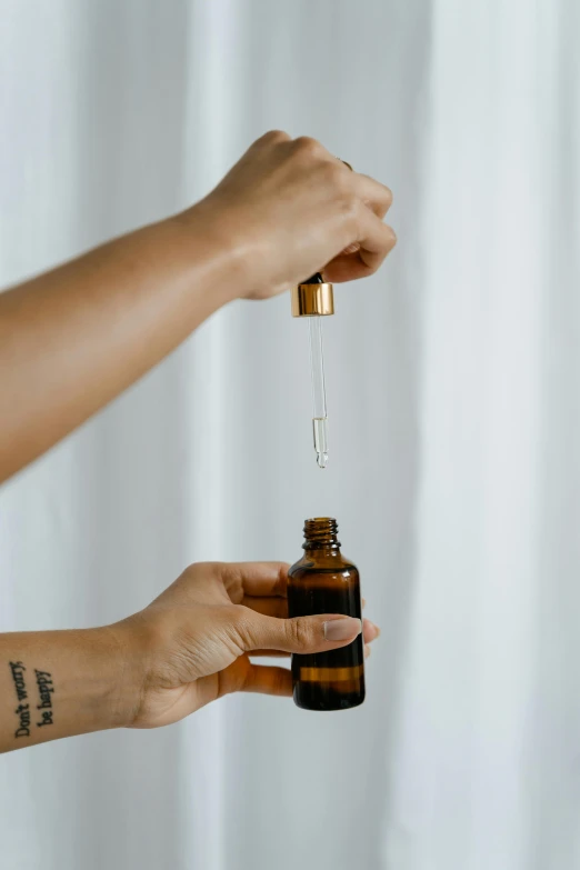 a close up of a person holding a bottle of essential oil, a picture, unsplash, hanging, holding a magic needle, brown, thumbnail