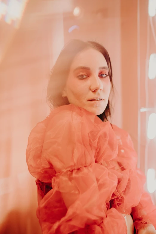 a woman standing in front of a mirror, an album cover, light red and deep orange mood, meredit frampton style, close up portrait shot, fluorescent