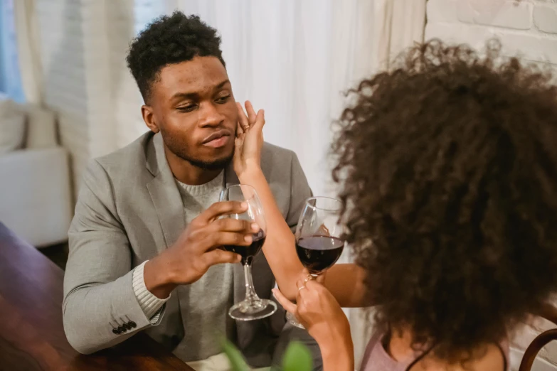 a man and a woman sitting at a table drinking wine, pexels contest winner, man is with black skin, greeting hand on head, broken down, post appocalyptic