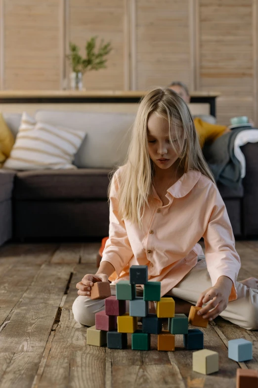 a woman sitting on the floor playing with blocks, pexels contest winner, screenshot from a movie, kids toy, square, scientific