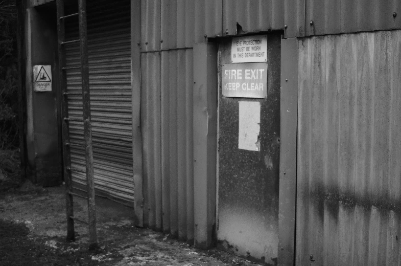 a black and white photo of a building, by David Allan, pexels, graffiti, rust and dust and fire and dirt, signboards, elstree, exiting store