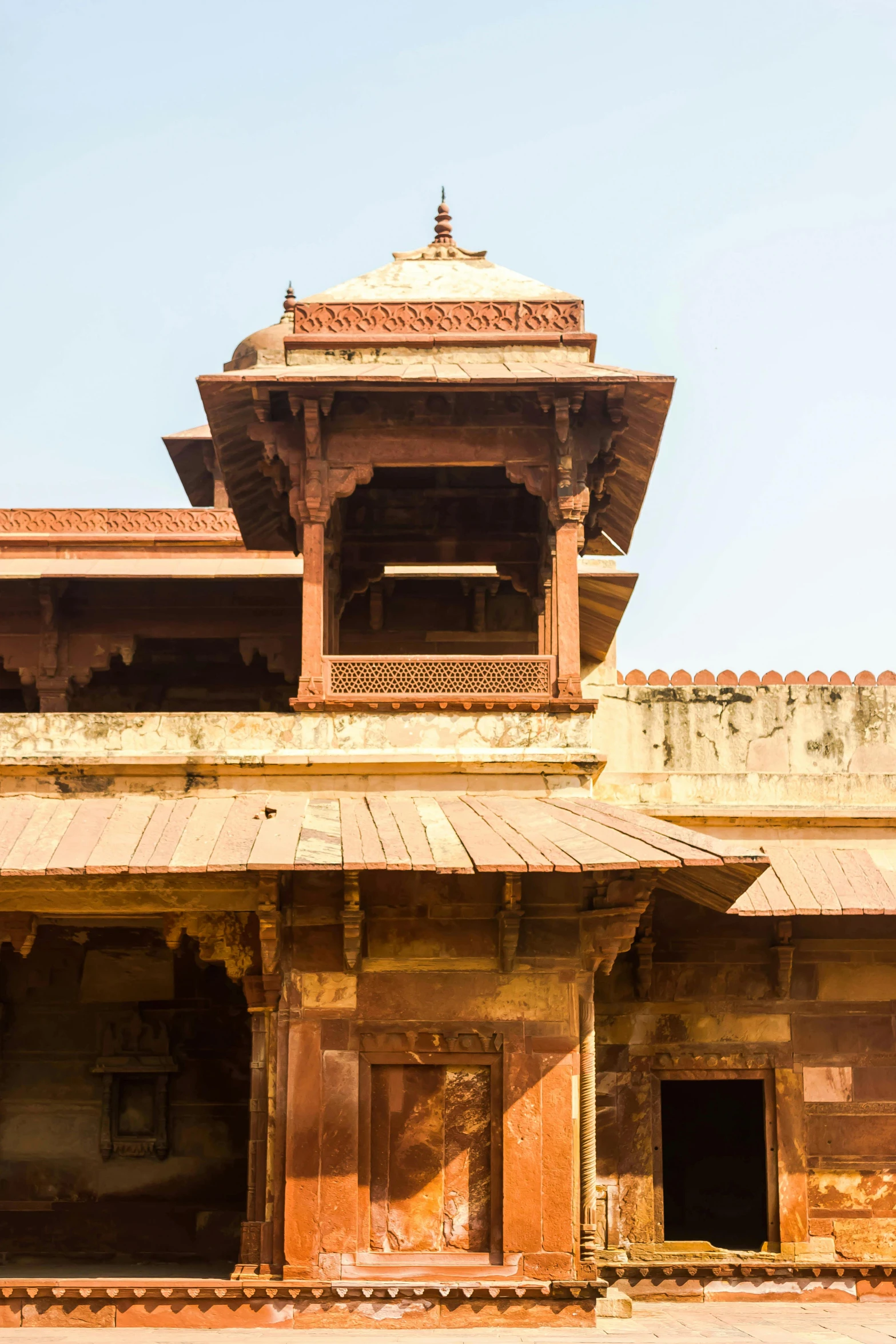 an old building with a clock tower on top of it, red sandstone natural sculptures, india, peaked wooden roofs, seen from below