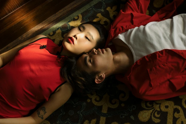 a man and a woman laying on the floor, a portrait, inspired by Nan Goldin, trending on pexels, traditional chinese clothing, red clothes, lesbians, jingna zhang