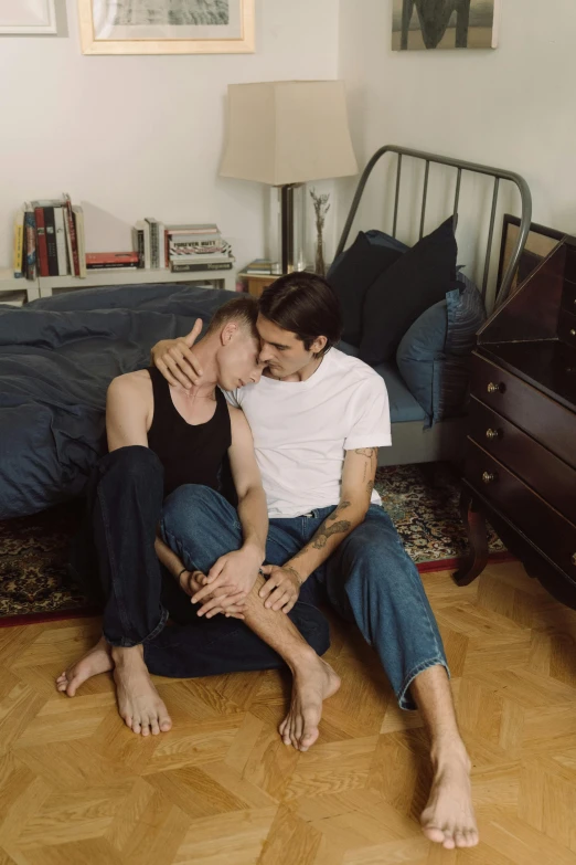 a couple of men sitting on top of a bed, by Elsa Bleda, trending on reddit, lesbian, greg rutkowski and alex ross, low quality photo, embrace