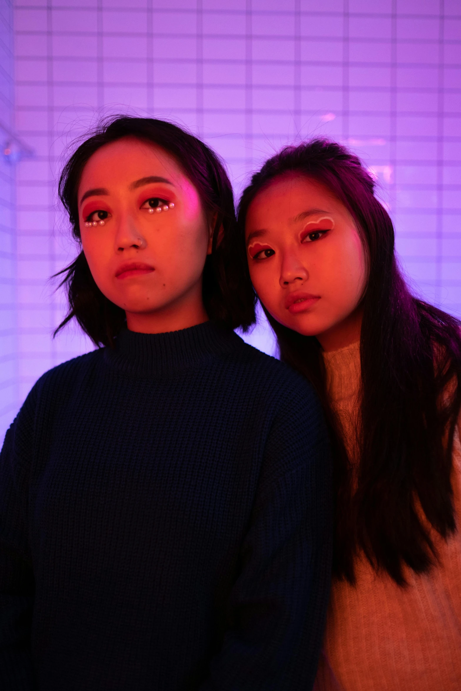 a couple of women standing next to each other, an album cover, inspired by Wang Duo, unsplash, realism, vibrant lights, half asian, looking serious, roomies