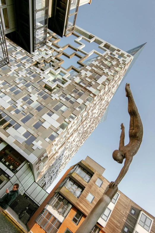 a statue of a man is in front of a building, inspired by Victor Enrich, unsplash, new sculpture, leaping towards viewer, utrecht, the cube, the shard