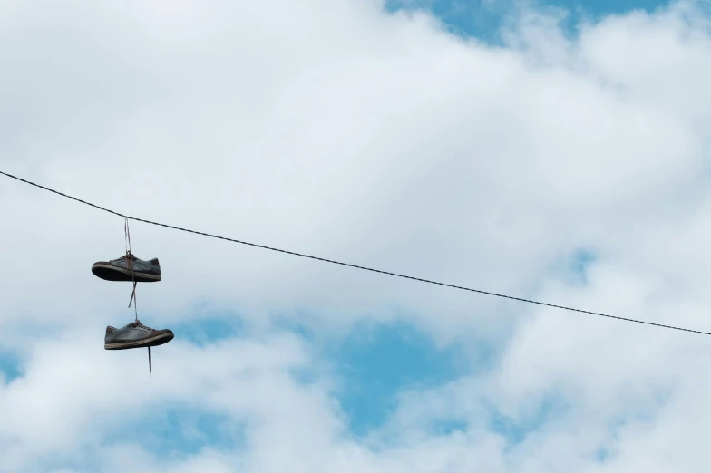 a pair of shoes hanging from a power line, unsplash, panorama view of the sky, taken with sony alpha 9, grey, outdoor photo