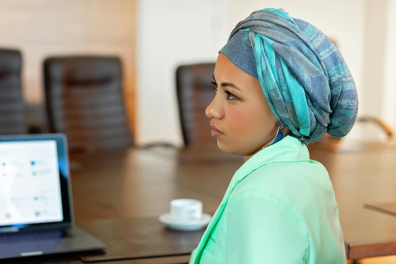 a woman sitting in front of a laptop computer, inspired by Nil Gleyen, pexels contest winner, hurufiyya, teal headband, an arab standing watching over, healthcare worker, profile image