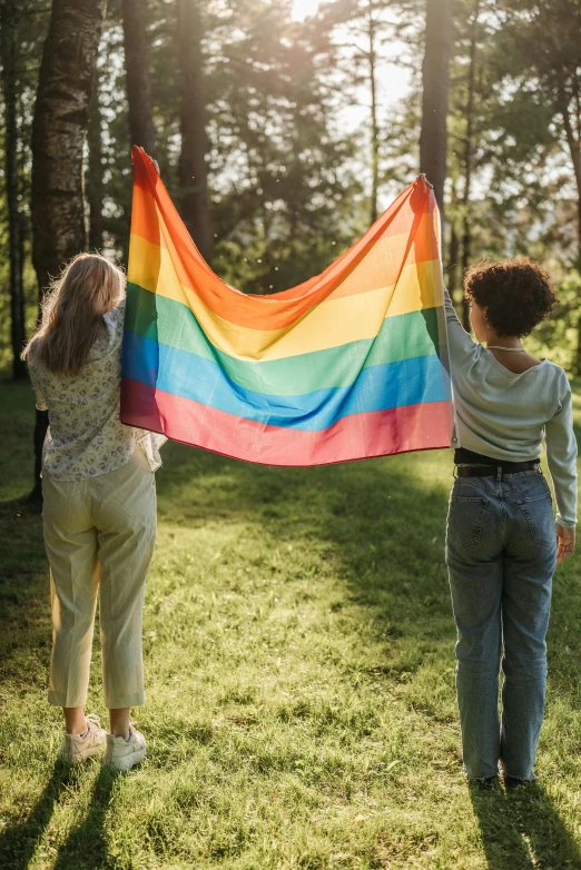 two women holding a rainbow flag in a park, long trunk holding a wand, 2019 trending photo, cute boys, diverse ages