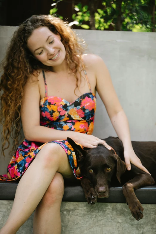 a woman sitting on a bench with a dog, brown curly hair, brooke ashling, portrait image, sleeveless