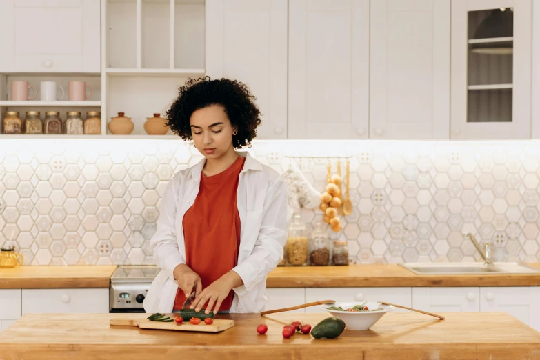 a woman cutting vegetables on a cutting board in a kitchen, by Julia Pishtar, pexels contest winner, wearing lab coat and a blouse, avatar image, cute woman, profile image