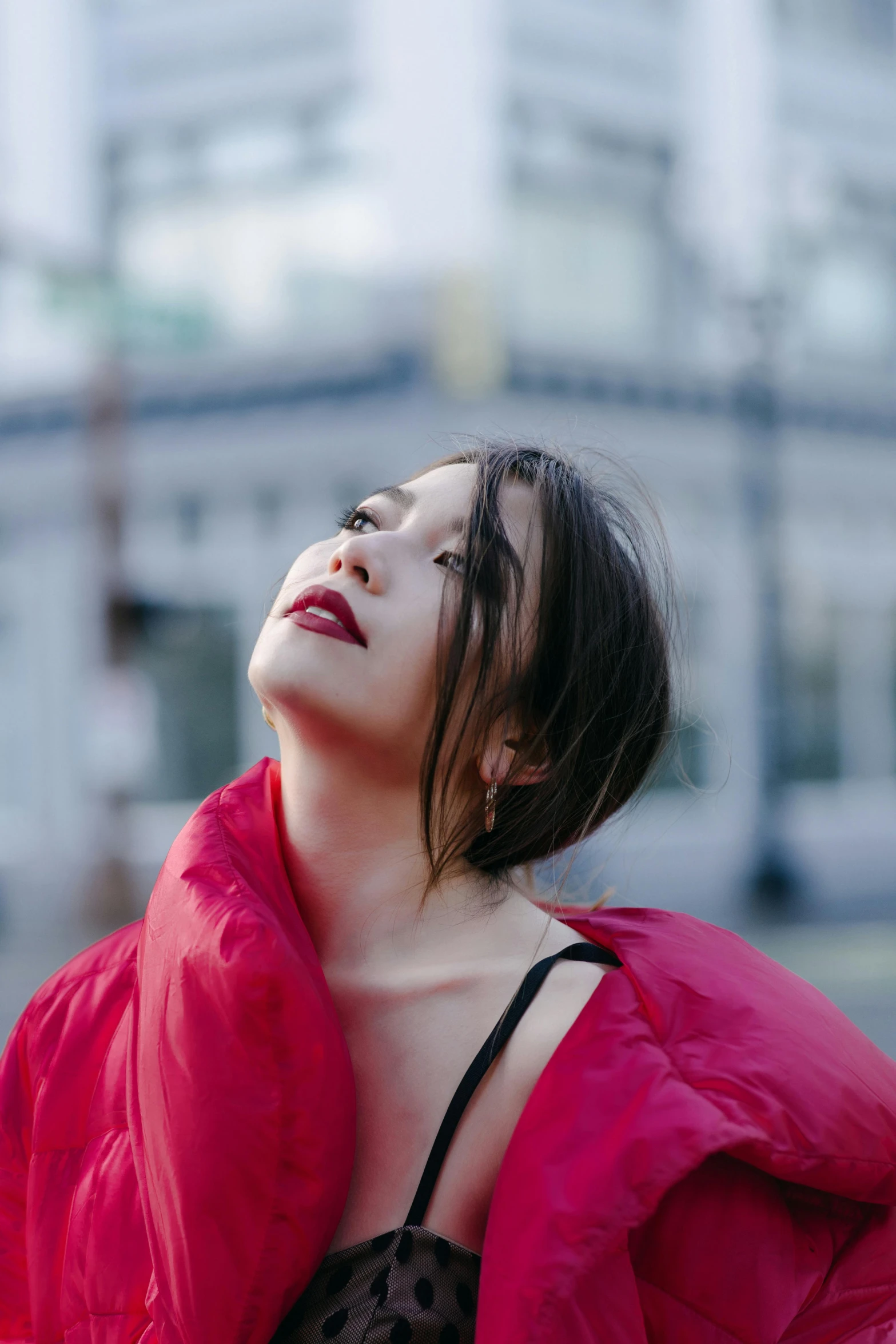 a woman in a red jacket standing in front of a building, an album cover, pexels contest winner, asian face, profile image, wearing shoulder cape, lipstick