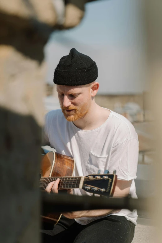 a man that is sitting down with a guitar, ginger hair with freckles, standing on a rooftop, performance, 1 / 4 headshot