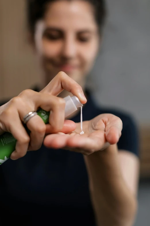 a woman holding a bottle of hand sanitizer, by Ben Zoeller, trending on pexels, renaissance, clean shaven, glue dropping, square, ultradetailed