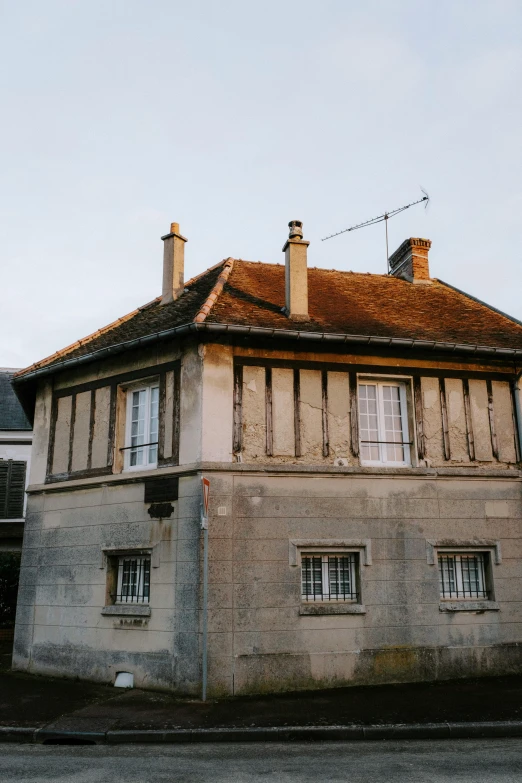 a building sitting on the side of a road, an album cover, inspired by Pierre Toutain-Dorbec, unsplash, renaissance, village house, square, normandy, late afternoon