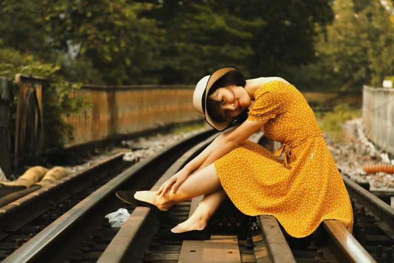 a woman in a yellow dress sitting on a train track, pexels contest winner, wearing a french beret, vintage dress, kiko mizuhara, sundress