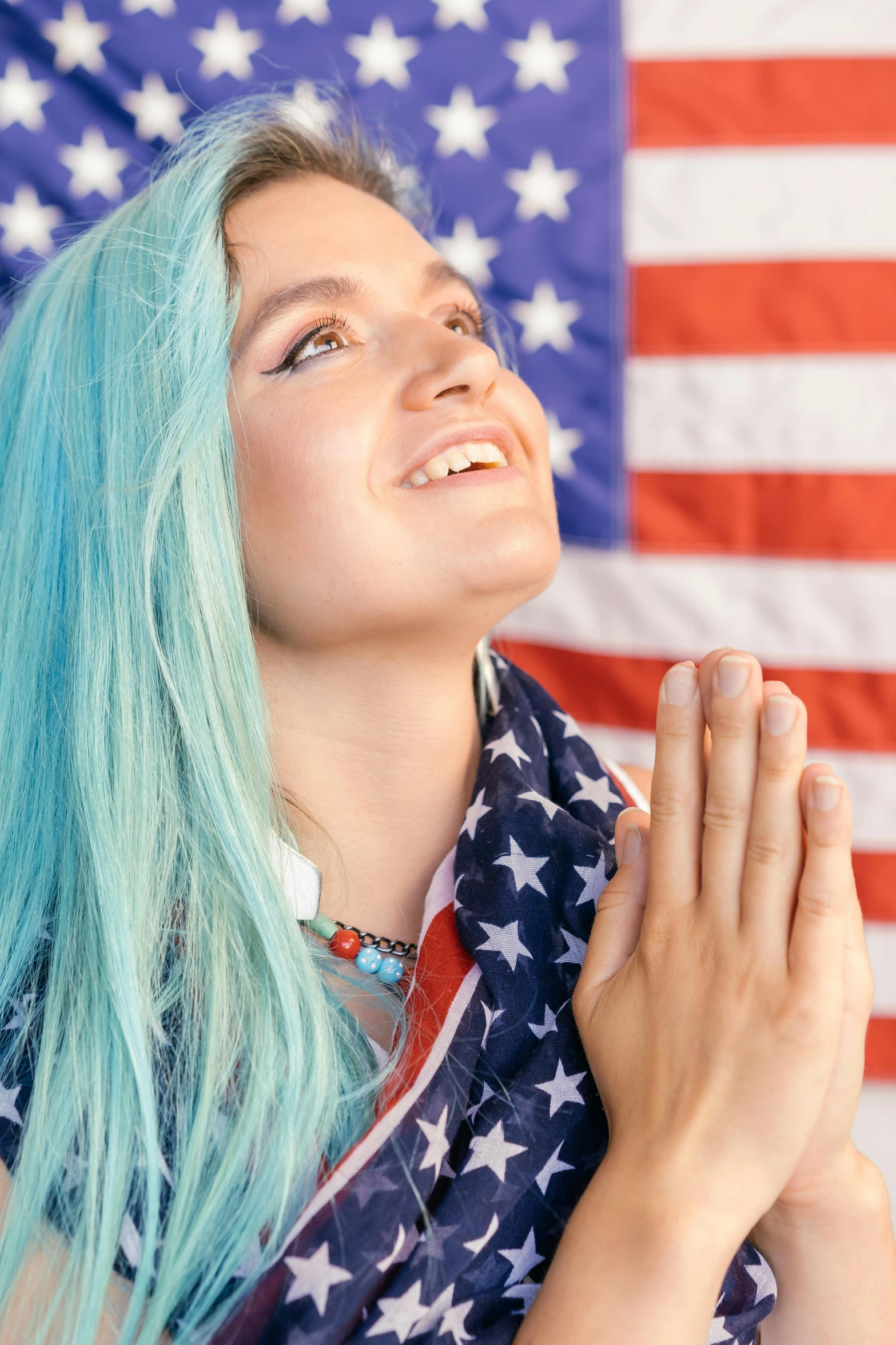 a woman with blue hair praying in front of an american flag, dye hair, proud smile, promo image, holy ceremony