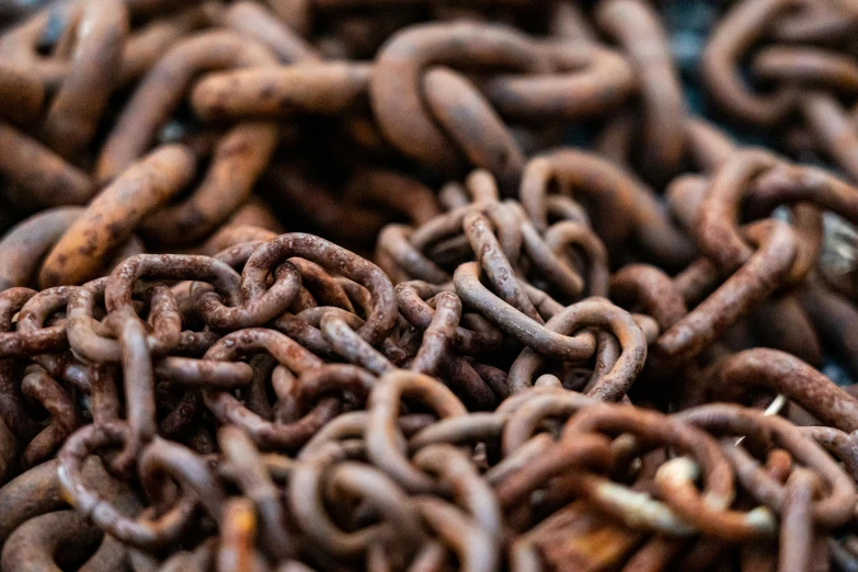 a pile of rusty chains sitting on top of a table, by Jay Hambidge, trending on pexels, process art, tentacle motifs, chocolate, zoomed in, fish hooks
