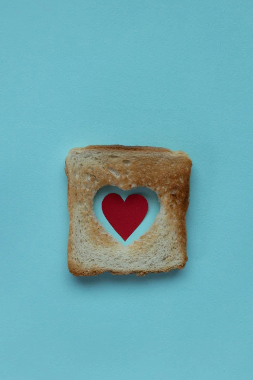 a piece of toast with a heart cut out of it, pexels, minimalism, with a blue background, square, breads, digital image