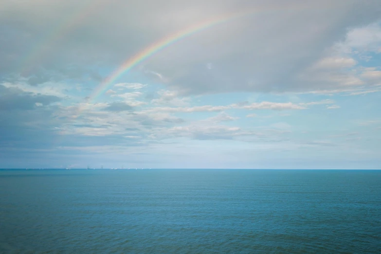a rainbow in the sky over a body of water, inspired by Elsa Bleda, unsplash contest winner, romanticism, blue sea, low quality photo, 8k resolution”, shot on hasselblad