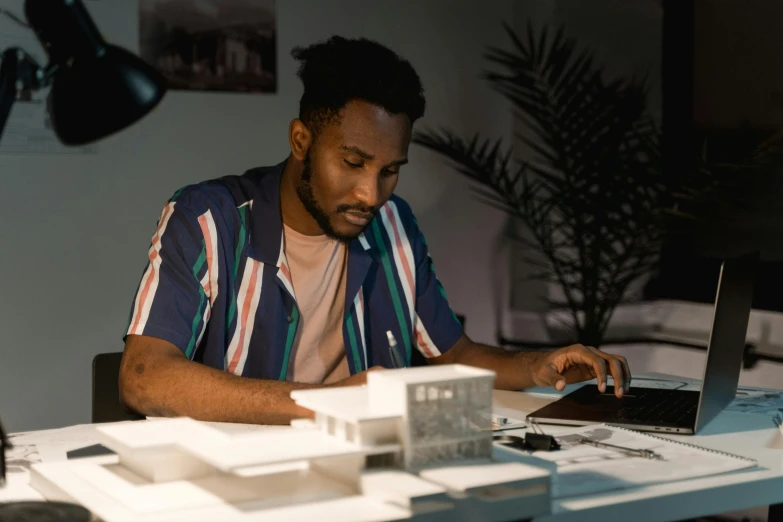 a man sitting at a desk using a laptop computer, a computer rendering, inspired by Afewerk Tekle, pexels contest winner, architectural model, low - lighting, : kendrick lamar, casually dressed