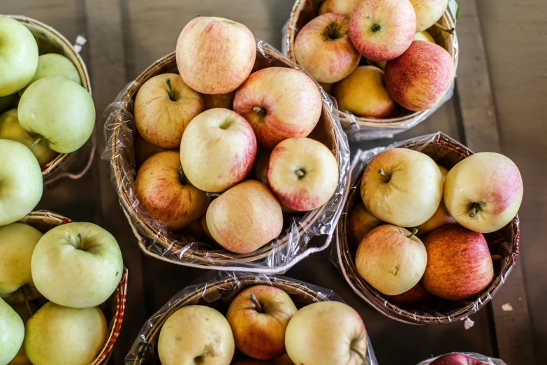 a number of baskets of apples on a table, by Niko Henrichon, pexels, fan favorite, sydney hanson, full product shot, manuka