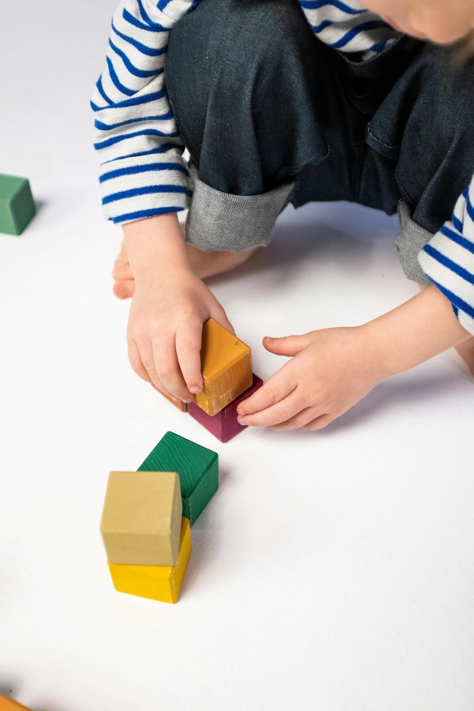 a little boy playing with wooden blocks on the floor, by Ruth Simpson, unsplash, visual art, solid colours material, on white background, detail shot, menger sponge