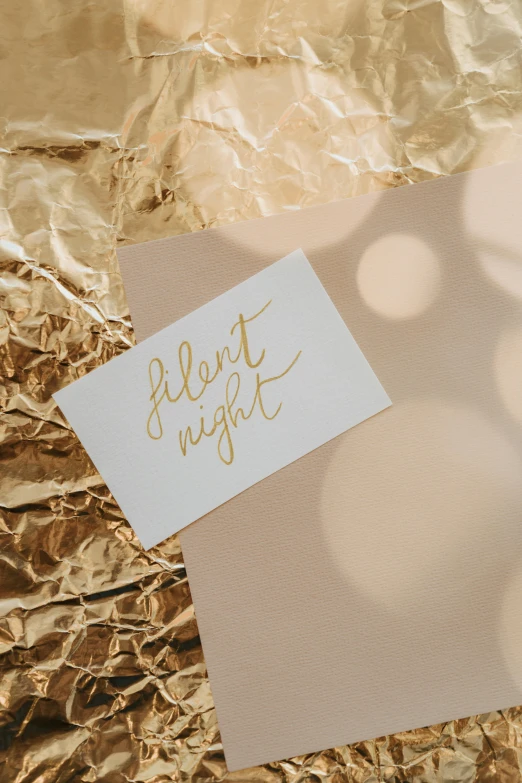 a note sitting on top of a piece of foil, pexels contest winner, light and space, subtle gold accents, matte print, card art, it's night