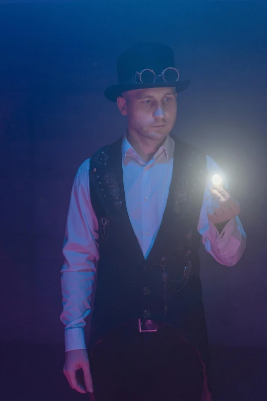 a man holding a light in his hand, a portrait, by Jason Felix, unsplash, holography, wearing steampunk top hat, model is wearing techtical vest, blue glow, hazy